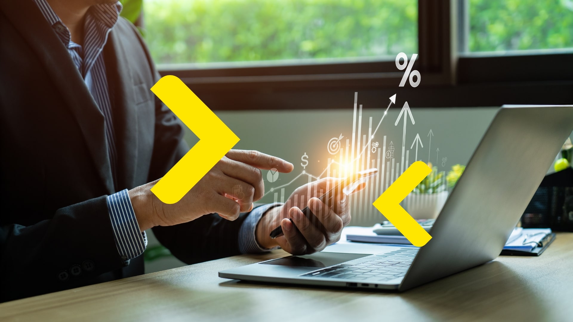 Muž v obleku pracuje na notebooku a mobilním telefonu