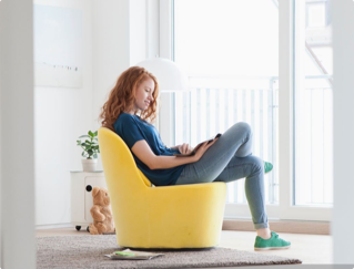 žena sedící ve žlutém křesle si čte